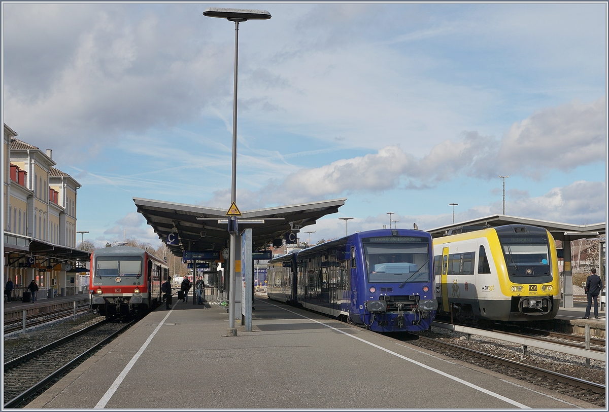 Bunte Bahn in Friedrichshafen: Nachdem die meisten roten Züge weggefahren waren, erreichte der  DB 612 571 mit einem weiteren VT 612 auf der Fahrt nach Aulendorf den Bahnhof Friedrichshafen und am Bahnsteig 3 trafen kurz darauf zwei blaue BOB VT 650 ein, während der DB 628 950 der Kurhessenbahn doch noch einen roten Akzent setzt; dazu ganz diskret und nur angedeutet das schön hergerichtet Bahnhofsgebäude.

16. März 2019