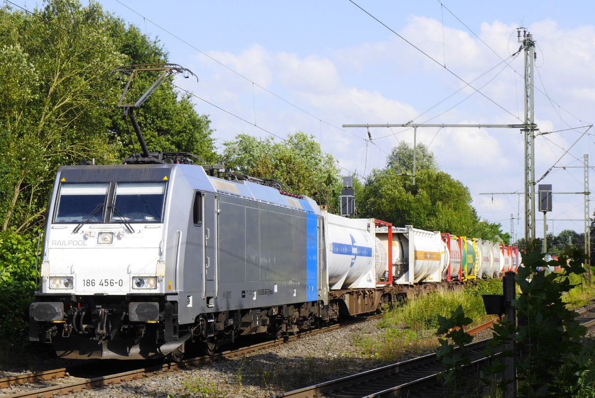 Bunte Reihe in grüner Niederrhein-Landschaft: 186 456-0 von Railpool muss mit ihrem langen Zug mit LKW-Aufligern und Containern auf ihrem Weg in die Niederlande in Boisheim den entgegenkommenden RE 13 abwarten. Aufnahme vom 29.7.16.