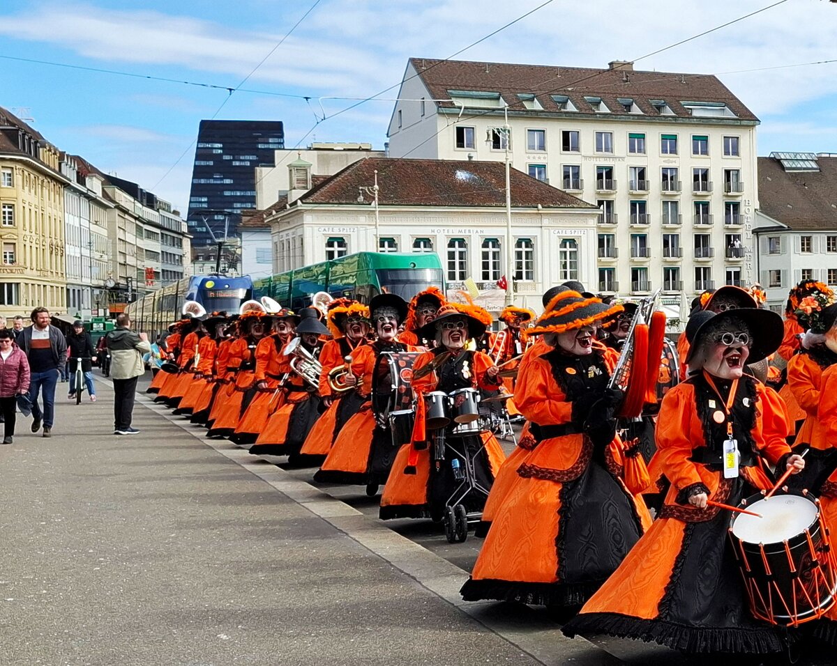 BVB und Basler Fasnacht__Immer wieder beeindruckend, wie reibungslos elegant dort sich die Kostümierten und auch bei den Umzügen die Zuschauer-Massen (die wie die Kostümierten und Musiker fast alle mit dem Tram in die Stadt strömen), miteinander und aneinander vorbei und zwischen den zahlreichen Trambahnen bewegen. Und so wie im Bild, auf der Rhein-Brücke, haben die Fasnachter natürlich Vorrecht, das Tram zuckelt hintendrein.__03-2025