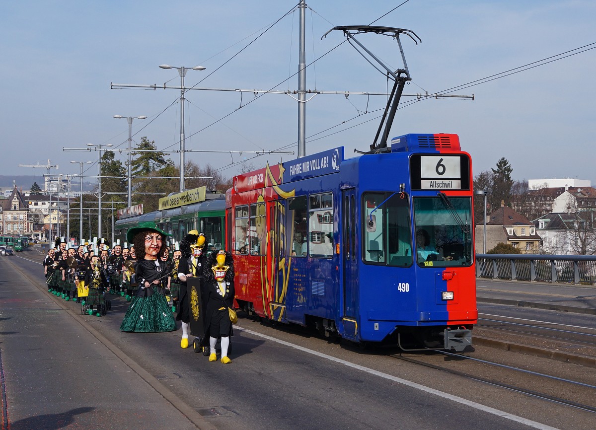 BVB während der BASLER FASNACHT 2014. Obschon während  den drey schenschte Dääg  nicht alle Linien auf den gewohnten Strecken verkehren, kommt es sehr oft zu Begegnungen zwischen Fasnachtscliquen und der BVB. Be 4/4 490 (Linie 6) mit Vollwerbung für den FCB und die GUGGENMUSIK  NUGGI SPUGGER  auf der Wettsteinbrücke am 11. März 2014.
Foto: Walter Ruetsch 