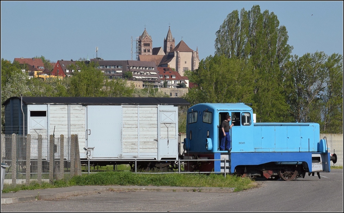 CFTR, die charmante Museumsbahn im Neubreisacher Urwald. Hier beim Depot der Museumsbahn am Rheinhafen Colmar/Neu-Breisach geht eine Sonderfahrt mit Dampfzug zu Ende. Die LKM V 22 schiebt nach, ja auch hier lebt die DDR noch... Als Loknummer bekam sie mit Orginalfabriknummer der LKM 262411. Im Hintergrund tront das Münster von (Alt-)Breisach auf der deutschen Rheinseite. Volgelsheim, April 2019.