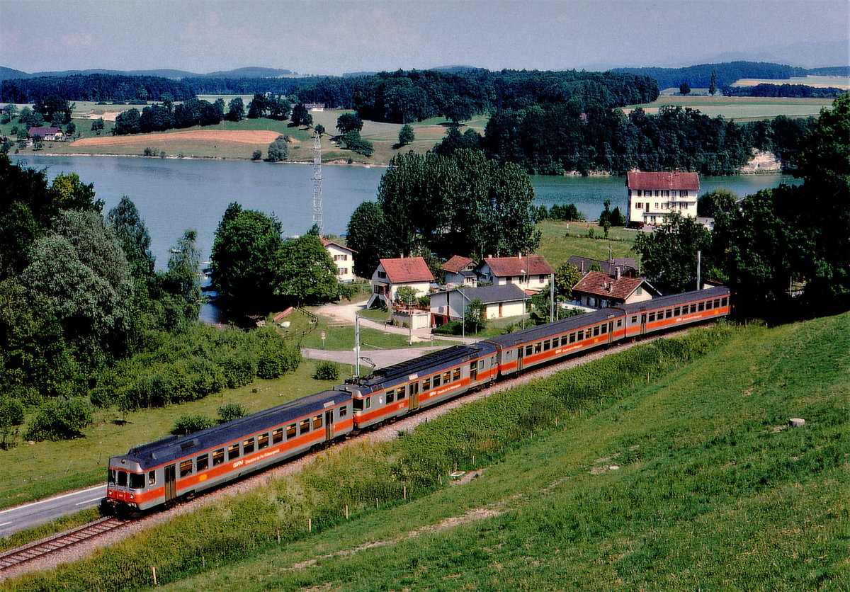 Chemins de fer Fribourgeois Gruyère-Fribourg-Morat GFM/TPF.
Verstärkter Regionalzug mit einem RABDe 4/4 171-172 am Schiffenensee bei Pensier unterwegs nach Ins im August 1984.
Foto: Walter Ruetsch
