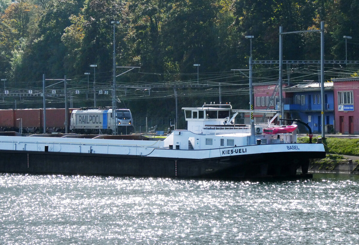 Containerzug wartet im Bahnhof Birsfelden Hafen hinter dem 'Kies-Ueli' auf die Abfahrt, gesehen von einem Schiff auf dem Rhein. Basel, 11.10.2025