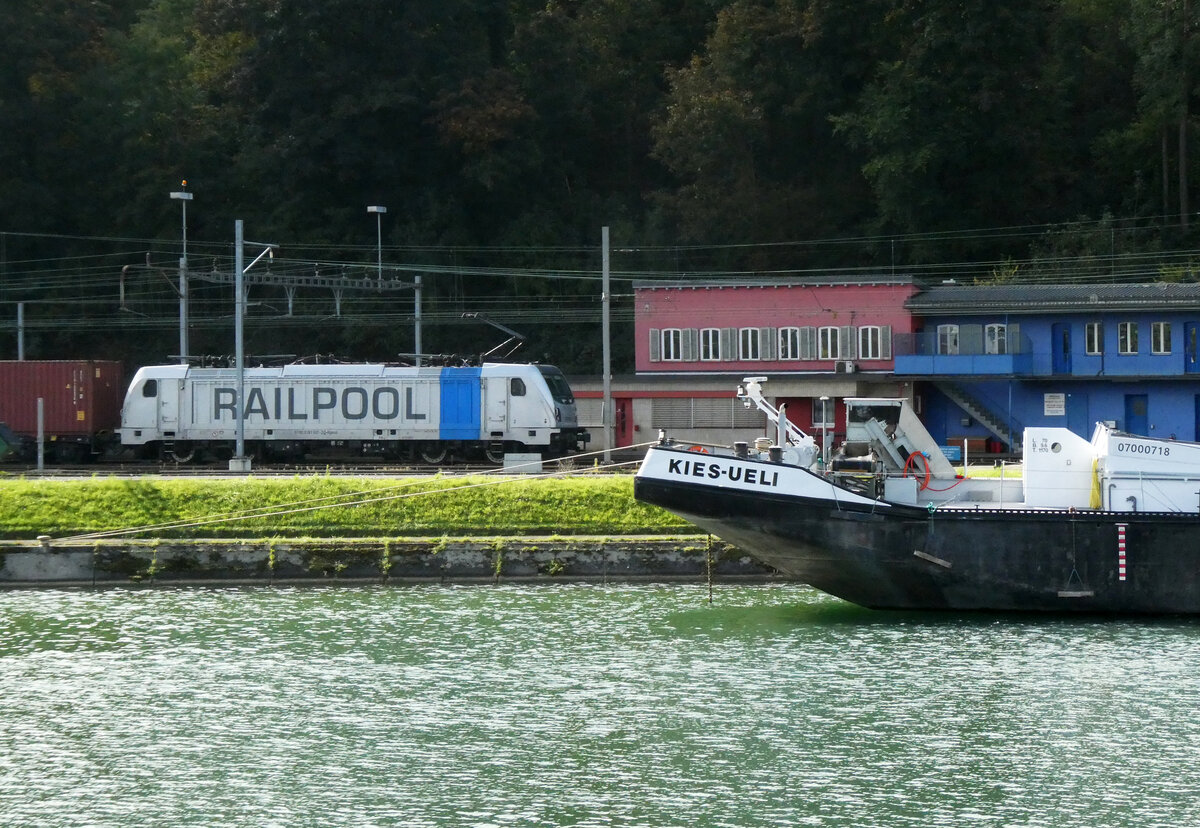Containerzug wartet im Bahnhof Birsfelden Hafen hinter dem 'Kies-Ueli' auf die Abfahrt, gesehen von einem Schiff auf dem Rhein. Basel, 11.10.2025