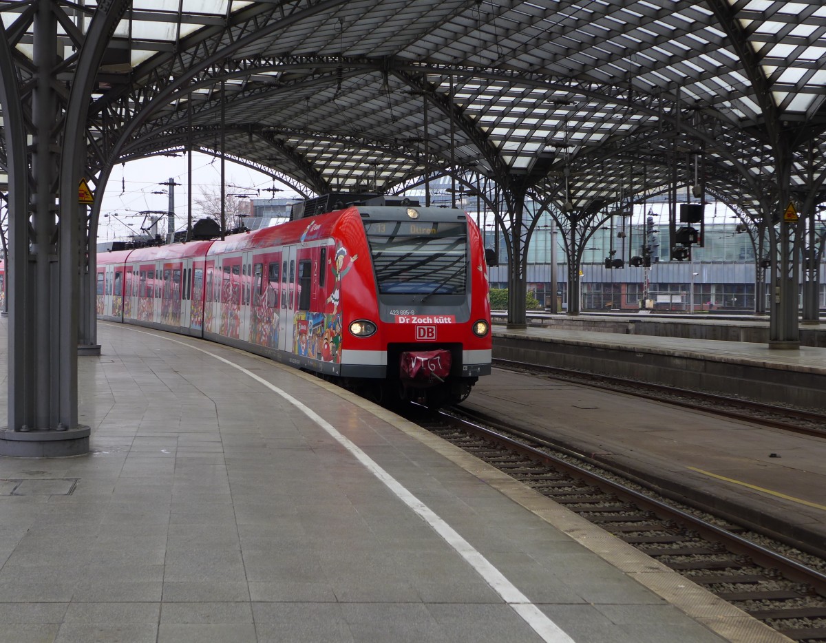 D´r Zoch kütt - 423 695-6 fährt zur Karnevalszeit mit entsprechnder Beklebung. Hier fährt er als S13 (Troisdorf - Düren) in Köln Hbf auf Gleis 8 ein. Aufgrund von Bauarbeiten an der S-Bahnstrecke in der Innenstadt halten die S-Bahnen in Köln Hbf und in Deutz auf den Gleisen des Regional- und Fernverkehrs, mit Ausnahme der S6. (05.03.2016)
