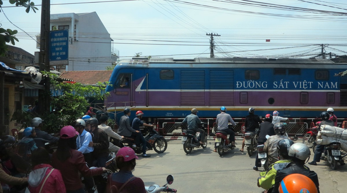 D19E-970 vorgespannt Schnellzug Saigon-Hanoi,Bahnübergang in Hue. Die Loks der Serie D19E wurden gebaut von CSR Ziyang Lokomotive Co.Ltd. Sichuan,China.Spurweite 1000mm,Gewicht 81t,Achsfolge CoCo,Diesel Caterpillar (US) 1455kw, Vmax.120km/h (24.3.14)