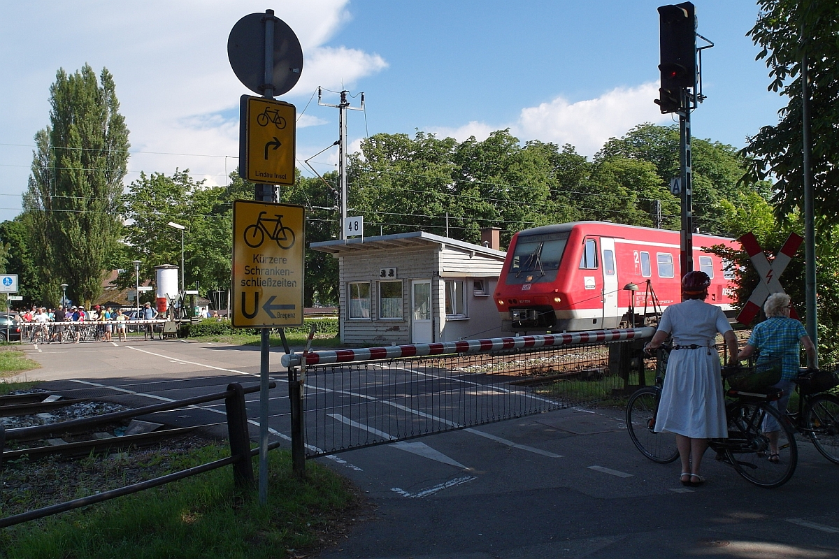 Da am Bahnübergang am Posten 48 in Lindau die Gleise von drei Strecken, der Vorarlberg-, Allgäu- und Bodenseegürtelbahn überquert werden müssen, kann es auf Grund der Zugdichte vorkommen, dass die Schranken mehr als 10 Minuten geschlossen bleiben. Damit beim Warten auf das Öffnen der Schranken die Geduld des einen oder anderen Fahrradfahrers nicht zu stark strapaziert wird, gibt es ein Hinweis-/Umleitungsschild zu Bahnübergängen mit kürzen Schrankenschließzeiten (05.06.2015).
