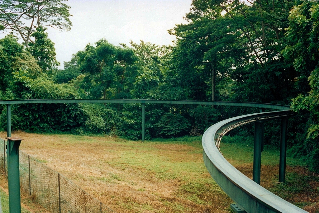 Da die SDC Sentosa Monorail als Rundkurs gegen den Uhrzeigersinn ausgeführt wurde war zur Zufahrt ins Depot bloß eine Weiche nötig. Als der Rundkurs auf im Uhrzeigersinn umgestellt wurde musste auch die Zufahrt zum Depot geändert werden. Das Bild vom 08.Mai 2002 zeigt die dafür errichtete Zufahrtsschleife zu Depot. Links unten im Bild erkennt man noch eine Stütze der ehemaligen Zufahrtsschiene. (Fotoscan)