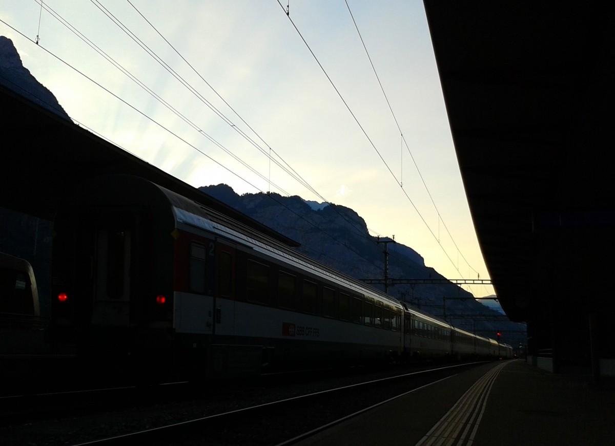 Dämmerung im Bahnhof Erstfeld. Hier verlassen soeben Re 460 081-3 und Re 460 031-8 am 21.7.2015 mit IR 2438 (Locarno - Zürich HB) den Bahnhof.