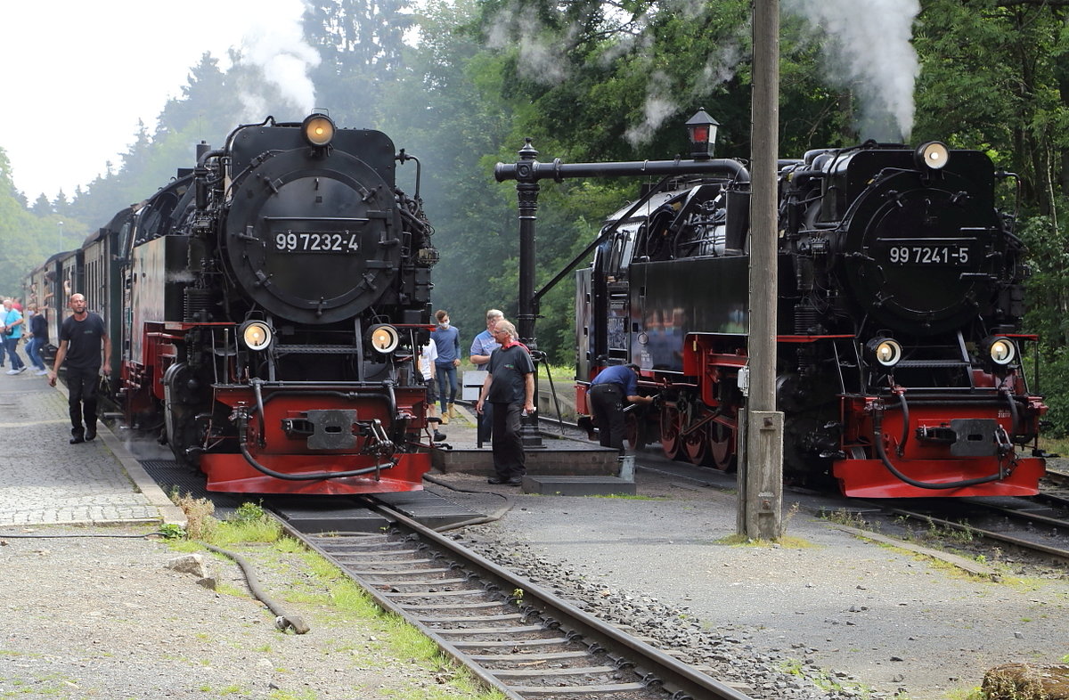 Dampflokalltag im Bahnhof Drei Annen Hohne: Während 99 7232 am Mittag des 22.08.2020 mit ihrem Oldie-Sonderzug zum Brocken eine Verschnaufpause einlegt und vom Lokpersonal eine kurze Inspektion erhält, hat  99 7241 sich von ihrem Zug P 8903 getrennt und ist zum Wasserkran vorgezogen. Während des Wasserfassens wird das Treibgestänge gründlich abgeschmiert. Danach geht sie wieder an den Zug und die fahrt nach Eisfelder Talmühle wird fortgesetzt.