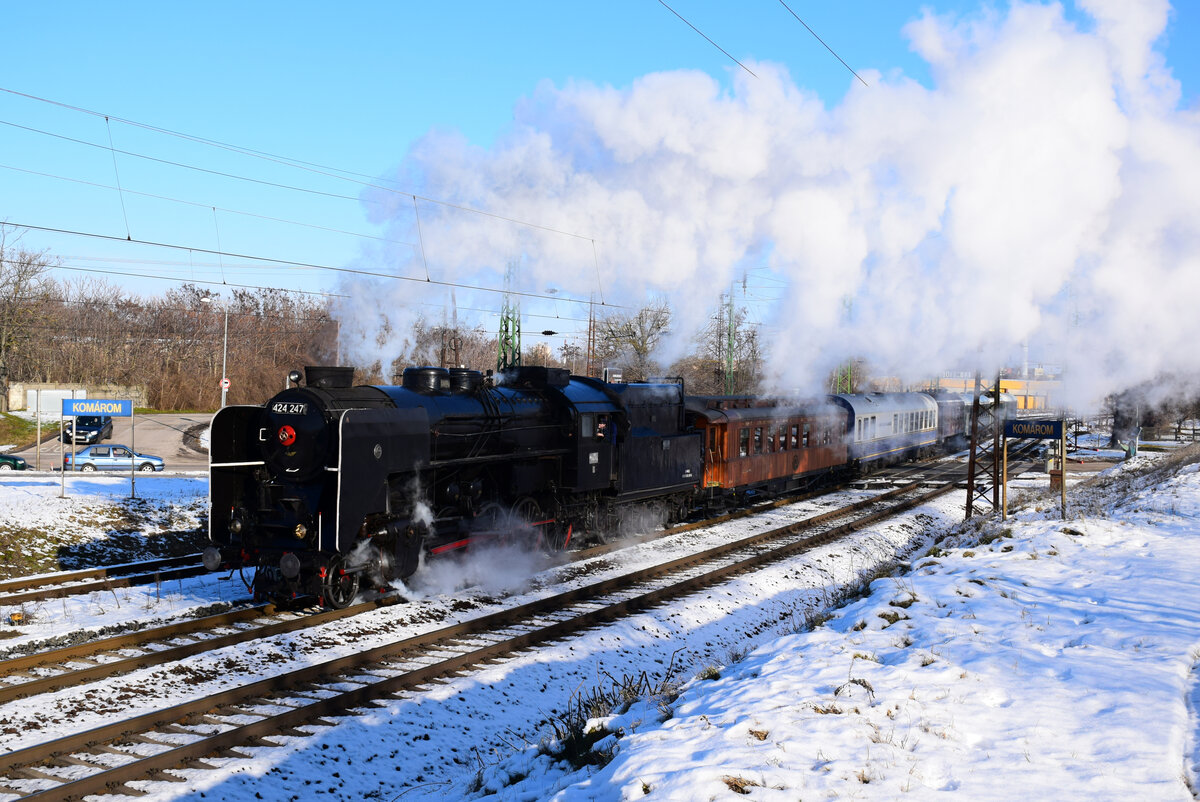 Dampfwolken auf der KBS 1! Die 424 247 mit dem  Arrabona Advent Express  kurz nach Komárom. 
Hinter der Lok ist der Teakholz-Wagen aus dem Jahr 1912.
Komárom, 12.12.2021.