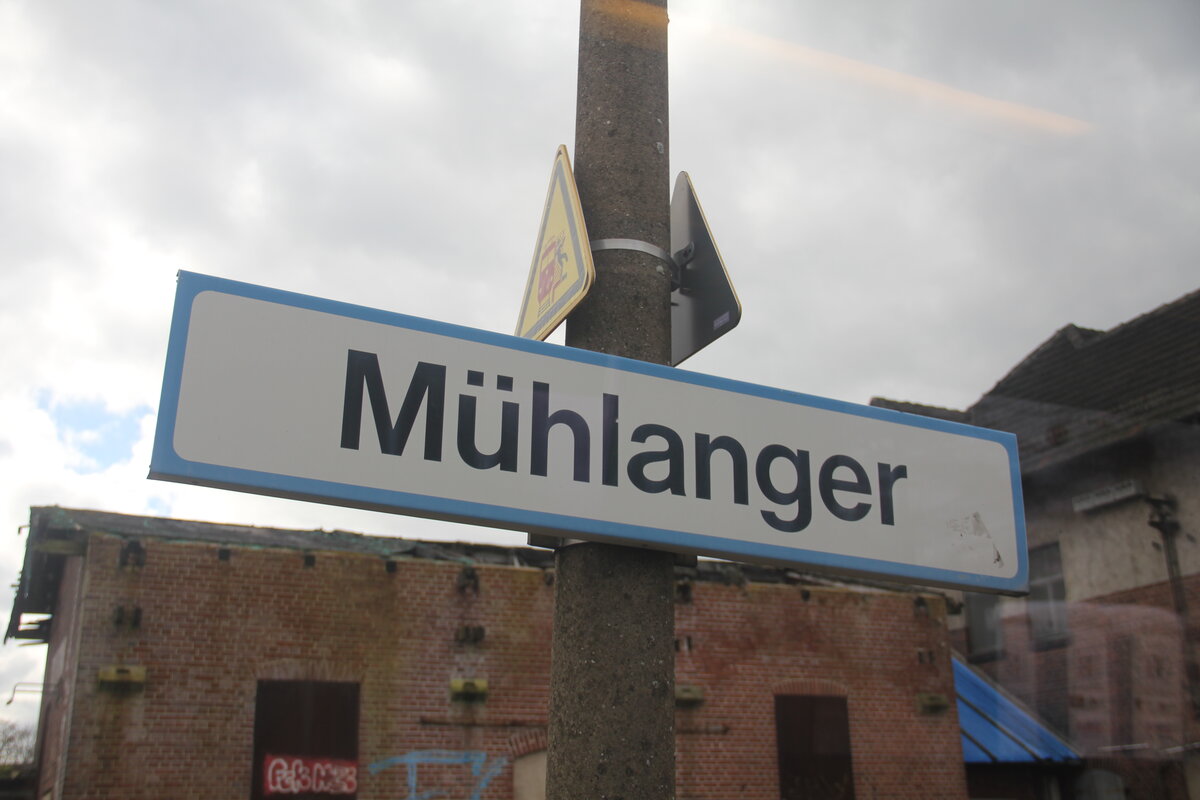 Das alte, Hellblau-weiße Bahnhofsschild am Haltepunkt Mühlanger. Wenn die Modernisierung von Bahnsteig 2 abgeschlossen ist, geht es auch diesem Schild an den Kragen.