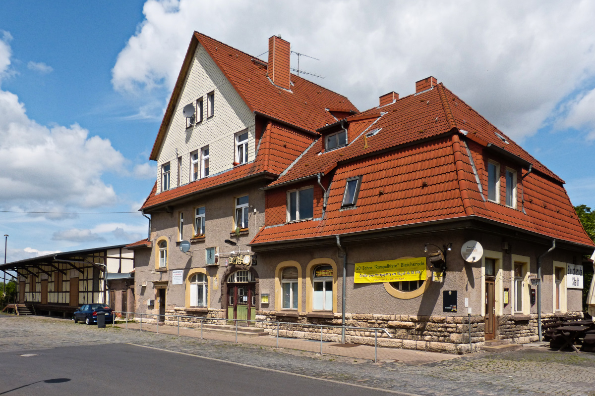 Das ehemalige Bahnhofsgebäude von Bleicherode - Stadt von der Straße aus. Das Bahnhofsschild rechts und links die Laderampe. 15.07.2015