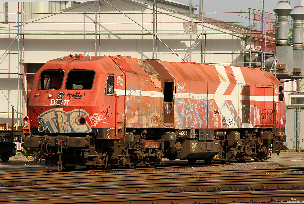 Das Ende für die Baureihe 240 (MaK DE1024) ist denkbar nah, DE11 hat man nach vorne geholt, DE13 steht in der Halle, wo ein Führerstand abgebaut wird und durch die KBEF erhalten wird. Anfang dieser Woche werden beide DE1024 lt meinen letzten Infos auf dem Gelände der benachbarten Firma Andryk zerlegt. Die 240 002 / DE12 weilt wohl noch in Kiel bei Voith, wo man versucht hat eine Hybridlok auf Basis der BR240 zu bauen, welches aber nicht weiter fortgeführt wurde. Aufgenommen am 09.08.2020, Standpunkt Kurfürstenstr, öffentl. zugänglich