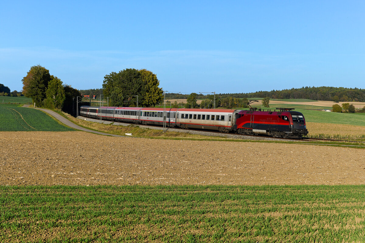 Das gab es schon länger nicht mehr. Im Herbst 2023 war die Strecke über den Arlberg gesperrt. In der jüngeren Vergangenheit bedeutete dies, dass die Nachtzüge und der Güterverkehr aus und in Richtung Vorarlberg in der Dunkelheit den Weg über das Allgäu nahmen. Die Reisezüge tagsüber wurden gebrochen und im Schienenersatzverkehr geführt. Diesmal gab es eine Ausnahme, der Transalpin wurde tagsüber umgeleitet. Interessant war hierbei auch, dass vor dem traditionsreichen Fernzug ausschließlich schweiztaugliche Railjet 1116er zum Einsatz kamen, die bis zum Zielbahnhof Zürich HB durchfahren konnten. So konnte die sonst erforderliche Zeit zum Umspannen eingespart werden, denn umleitungsbedingt entfiel der Fahrtrichtungswechsel in Buchs. Am 13. Oktober 2023 konnte die 1116.203 mit dem Transalpin bei Kottgeisering fotografiert werden. Beinahe hätte ein Disput mit dem Eigner des Feldes das Bild nicht möglich gemacht. Dieser zeigte sich kurz vor Durchfahrt des EC 164 noch einsichtig und gestatte dann doch das Betreten seines Grund und Boden.  