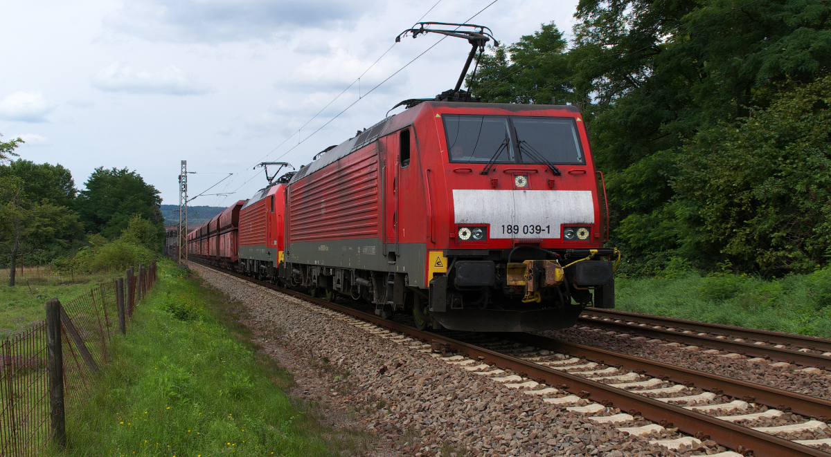 Das  Hightlight  wie es im Neudeutschen so schön heiß ist auf der Saarstrecke natürlich der  Lange Heinrich  oder  Erzbomber . Schon lange kommt er nicht mehr aus dem Emsland, sondern aus Rotterdam Maasvlakte. 189 039 + 189 046 bringen die schwere Last zur Dillinger Hütte. Hier etwa 1,5 Km vor dem Abzweig zur Hütte bremst der Zug schon ein und ist nicht mehr all zu schnell unterwegs. Man spürt richtig die Wärme der beanspruchten Bremsen. Strecke 3230 am 06.08.2014 in Dillingen Pachten.