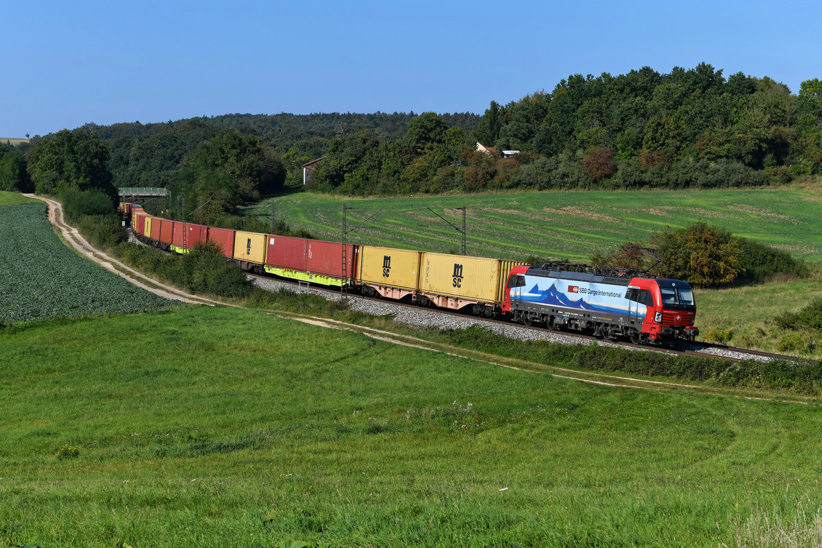 Das Stativ war bereits abgebaut, die Kamera eingepackt und ich bereits auf dem Rückweg zum Auto, als diese fotogene Leistung auftauchte. Der DGS 88129 von Dradenau nach Regensburg Ost wies am 15. September 2020 einige Stunden Verspätung auf und lag daher an der S-Kurve bei Edlhausen in der Oberpfalz noch gut im Licht. Bespannt wurde der komplett beladene Containerzug von dem SBB Cargo Vectron 193 470.