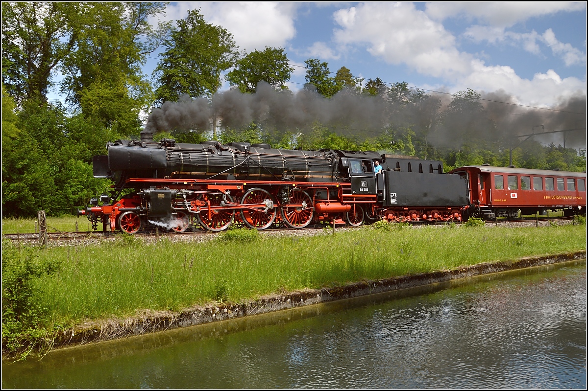 Das Wochenende am Bodensee ist beendet und der Zug mit 01 202 ist auf dem Rckweg. Bei Brglen am Thurkanal kommt sie mit deutlich vor Fahrplan mit Volldampf vorbeigerauscht. Mai 2015.