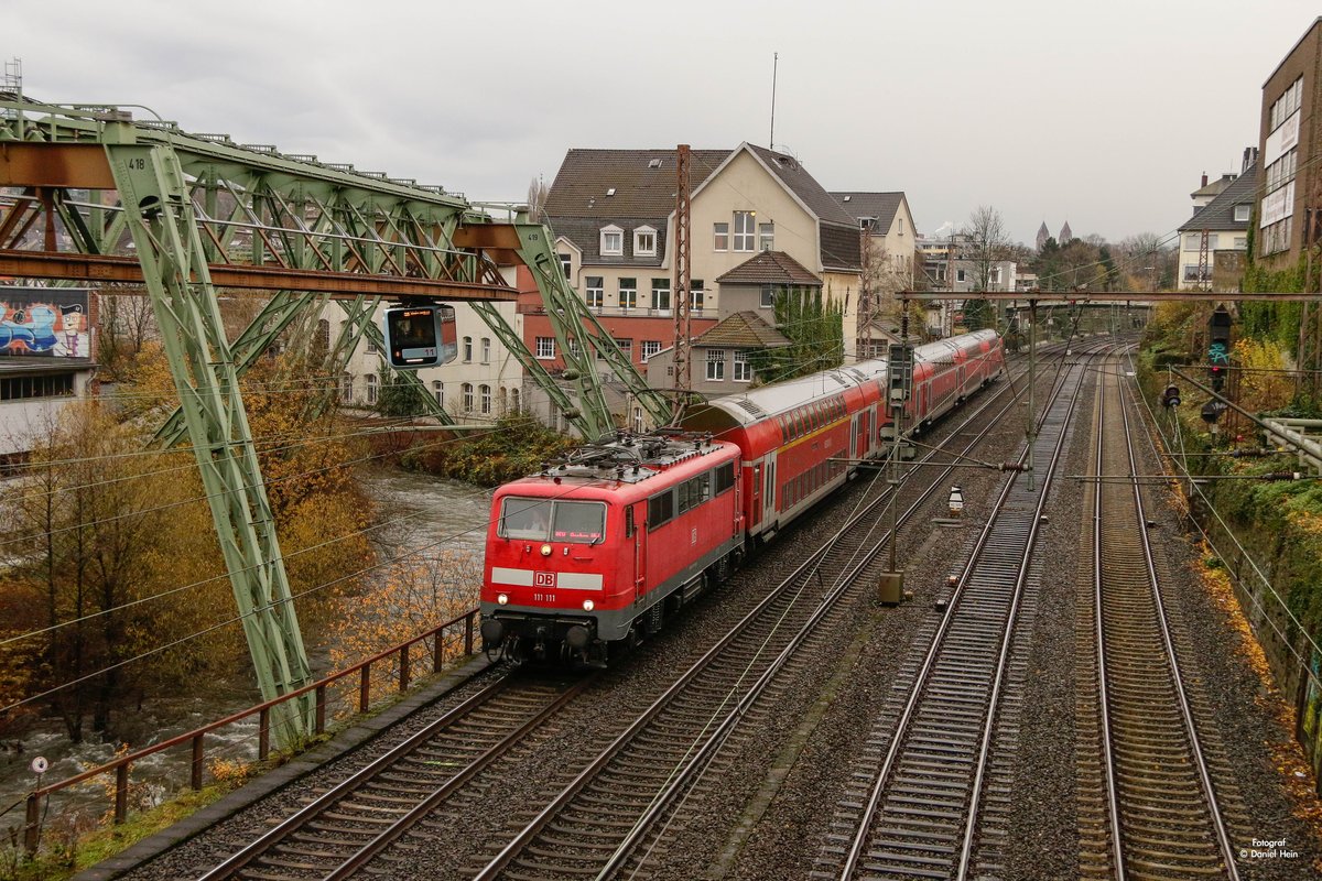 DB 111 111 mit RE4 und links die neue Schwebebahn 11 in Wuppertal, November 2017.