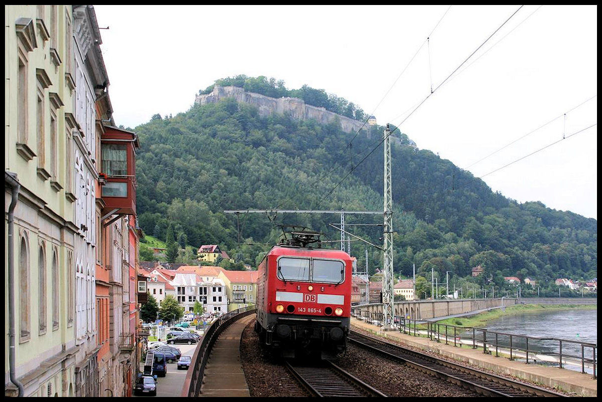 DB 143865-4 fährt hier am 27.8.2006 mit einem RE aus Dresden in den Bahnhof Königsstein ein. Im Hintergrund bildet die gleichnamige Festung eine dazu passende Kulisse.