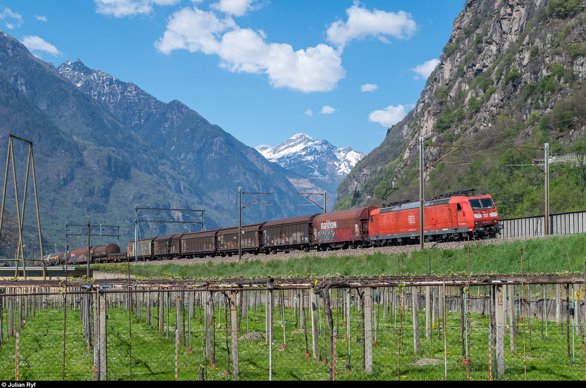 DB 185 097 ist am 10. April 2017 bei Pasquerio mit einem gemischten Güterzug auf der alten Strecke via Bahnhof Biasca unterwegs. <br>
In der Zeit, wo der Güterzug von der Basisstrecke ausfädelt und den Bahnhof Biasca durchfährt, wird er über die neue Umfahrung Biasca vom nachfolgenden schnellen Personenzug überholt, der erst nach Biasca wieder die alte Strecke erreicht.