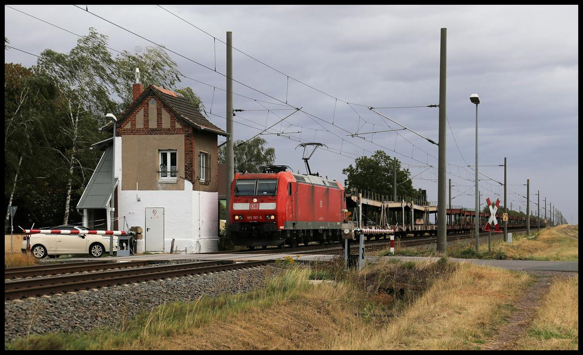 DB 185157-6 passiert hier am 26.08.2020 um 10.53 Uhr mit einem leeren Autotransportzug in Richtung Halle an der Saale den Schrankenposten bei Braschwitz.