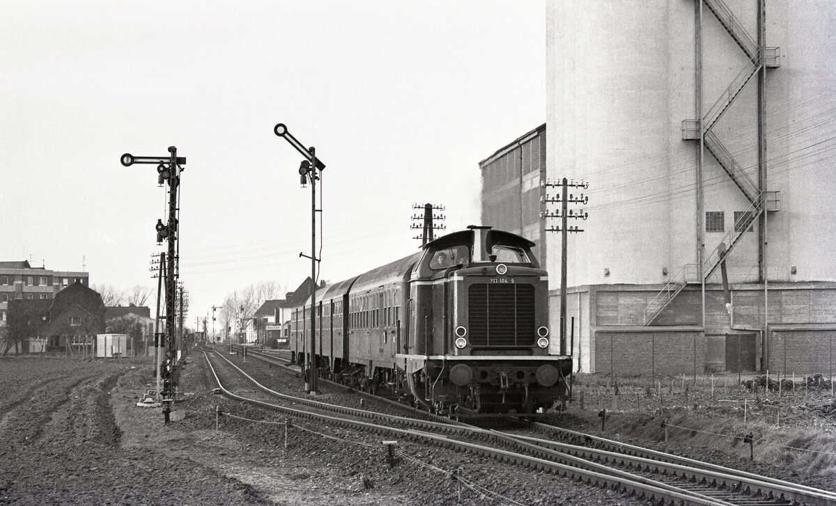 DB 211 104-5 verlässt den Bahnhof Kalkar am 21.02.1977 mit E-3791 von Kleve nach Duisburg Hbf. Nach rückbau der Strecke wurde das Bahngelände mittlerweile total überbaut. Scanbild 90926, Kodak Tri-X.