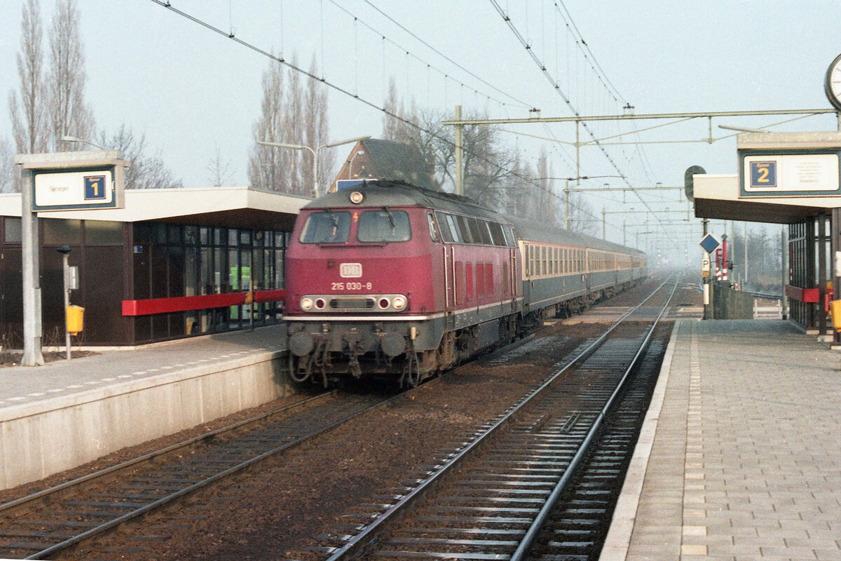 DB 215.030-8 mit D-417 (Amsterdam CS - München Hbf) bei der Durchfahrt des Bahnhofes Elst am 15.02.1981, ca 10.20u. Weiterfahrt des Zuges über Nijmegen, Kleve und Krefeld. Scan (Bild 2171, Kodacolor400).