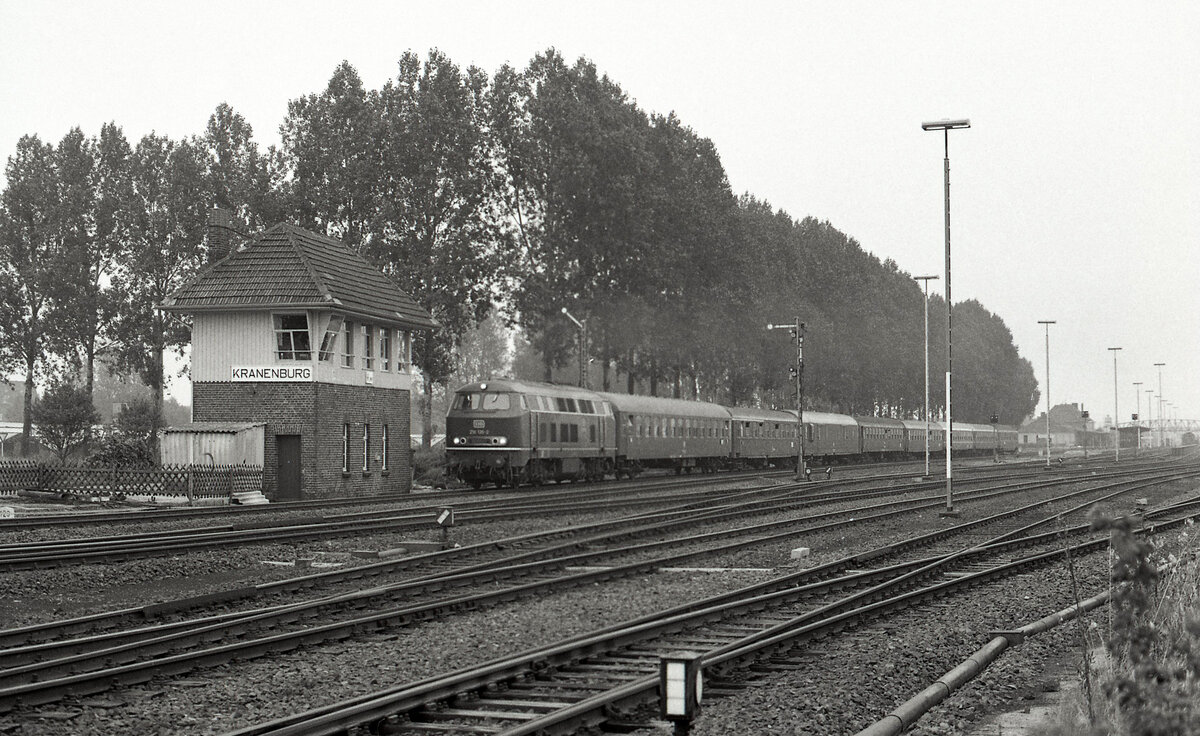 DB 218 135-2 mit D-216  Austria Expres (Klagenfurt Hbf - Amsterdam CS) bei der Abfahrt in Kranenburg am 08.09.1977. Links Stellwerk  Kw . Scanbild 91204, Ilford FP4.