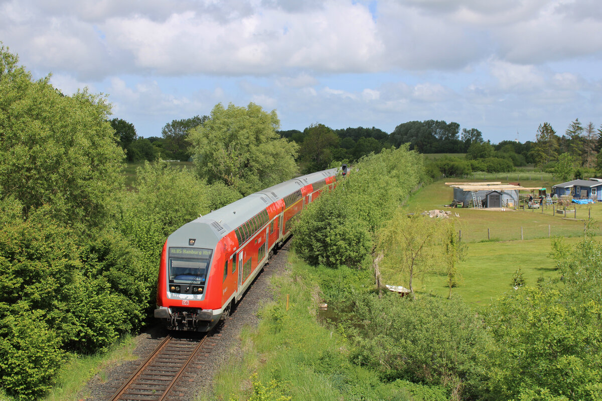 DB 218 470-3 schiebt den Strand-Express von Puttgarden über die Vogelfluglinie in Richtung Hamburg und verlässt hier gerade nach einer Zugkreuzung den Betriebsbahnhof Beschendorf.