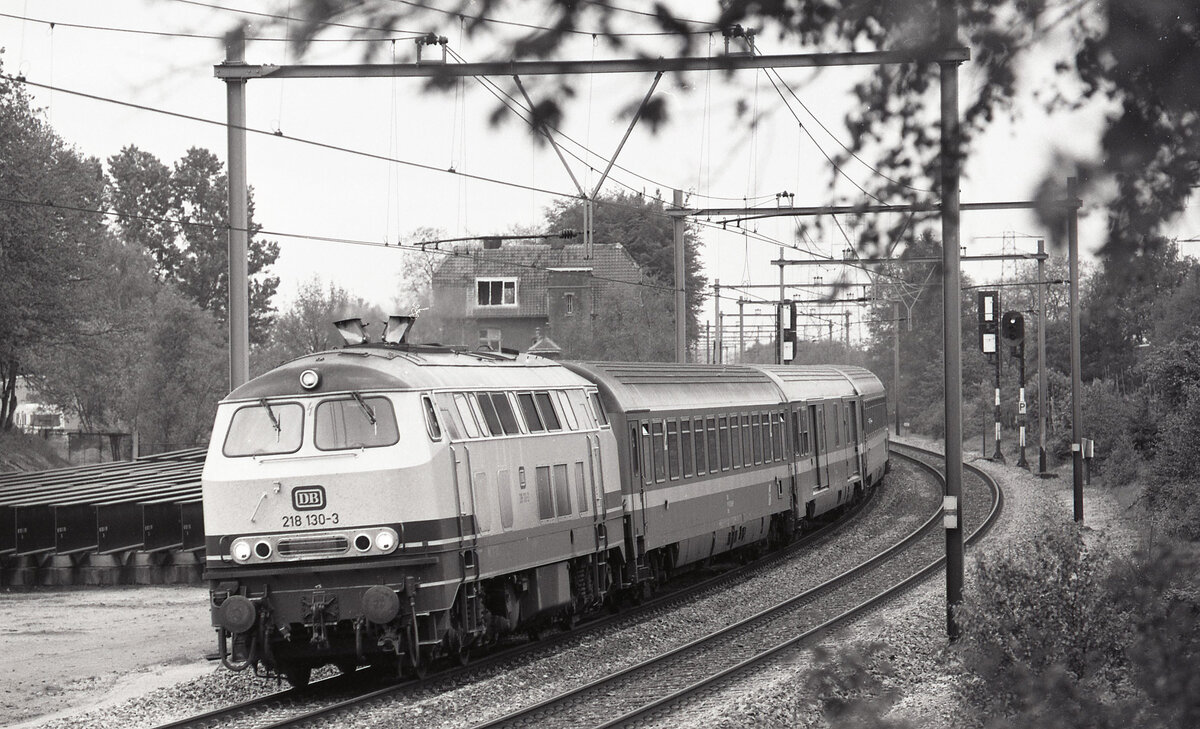 DB 218.130-3 mit D-216  Austria Expres  (Klagenfurt Hbf - Amsterdam CS) bei Durchfahrt des ehemaligen Bahnhofes Oosterbeek Laag am 11.05.1987. Der Zuglauf führte über Krefeld, Kleve und Nijmegen. Scan (Bild 94518, Ilford FP4).