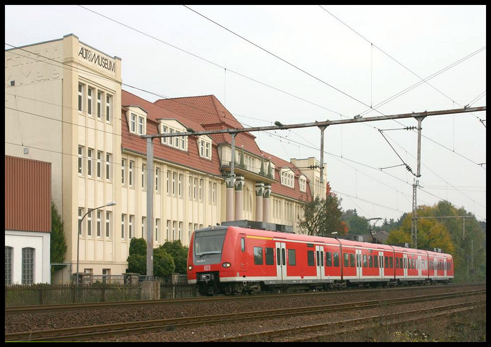 DB 425156 verlässt hier am 9.10.2005 als RB nach Bad Bentheim den Bahnhof Melle. Im Hintergrund das mächtige Gebäude des dortigen Automuseums. Einst war es eine große Möbelfabrik.