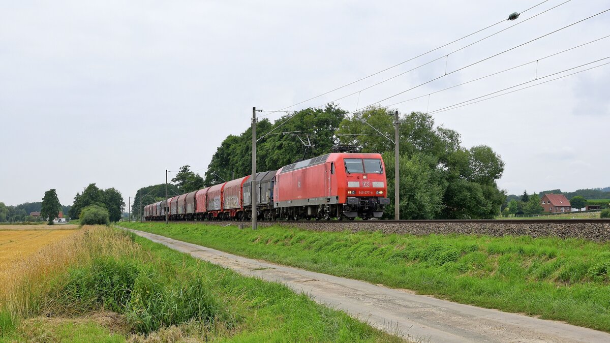 DB Cargo 145 077 mit einem Schiebehauben- und mehreren Schiebeplanwagen in Richtung Löhne (bei Melle, 21.07.2021).