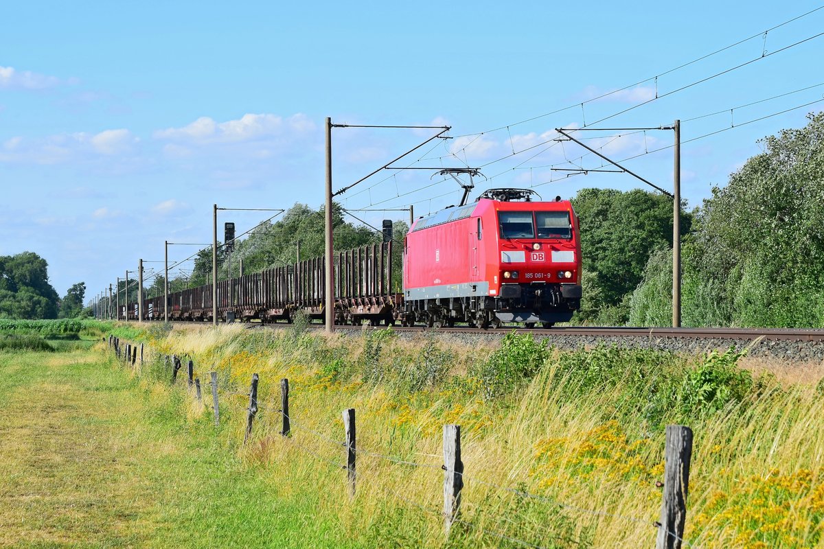 DB Cargo 185 061 mit leerem Rungenwagenzug in Richtung Osnabrück (Hüde, 01.07.19).