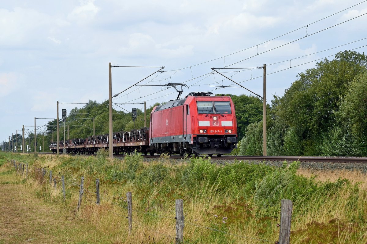 DB Cargo 185 247 mit kurzem Zug aus mit Drehgestellen beladenen Flachwagen in Richtung Osnabrück (Hüde, 08.08.19).