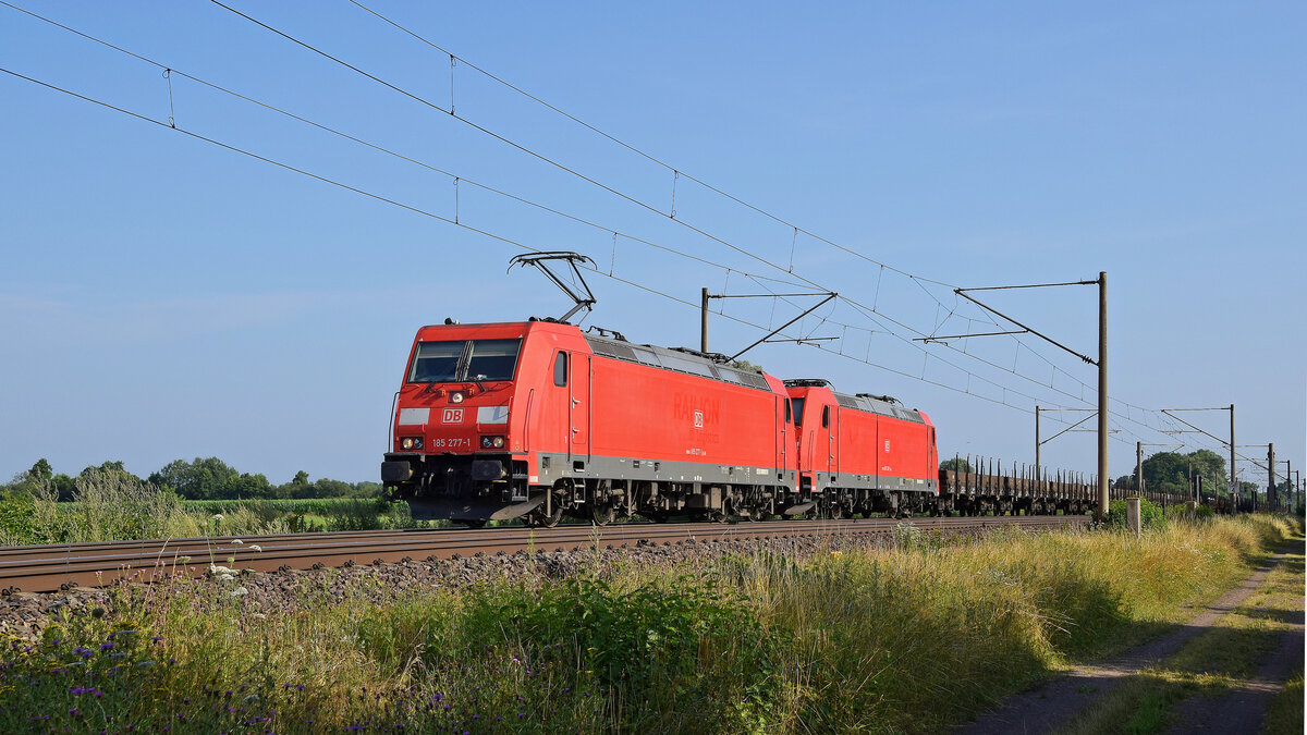 DB Cargo 185 277 mit Wagenlok DB Cargo 185 220 und Niederbord-Rungenwagenzug in Richtung Osnabrck (Hde, 24.07.2021).