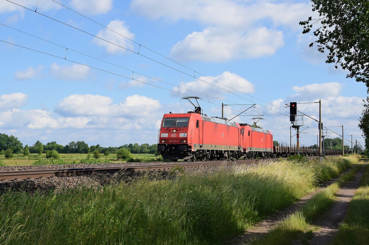 DB Cargo 185 391 und 185 XXX mit Niederbordwagen in Richtung Osnabrück (Hüde, 19.06.2021).