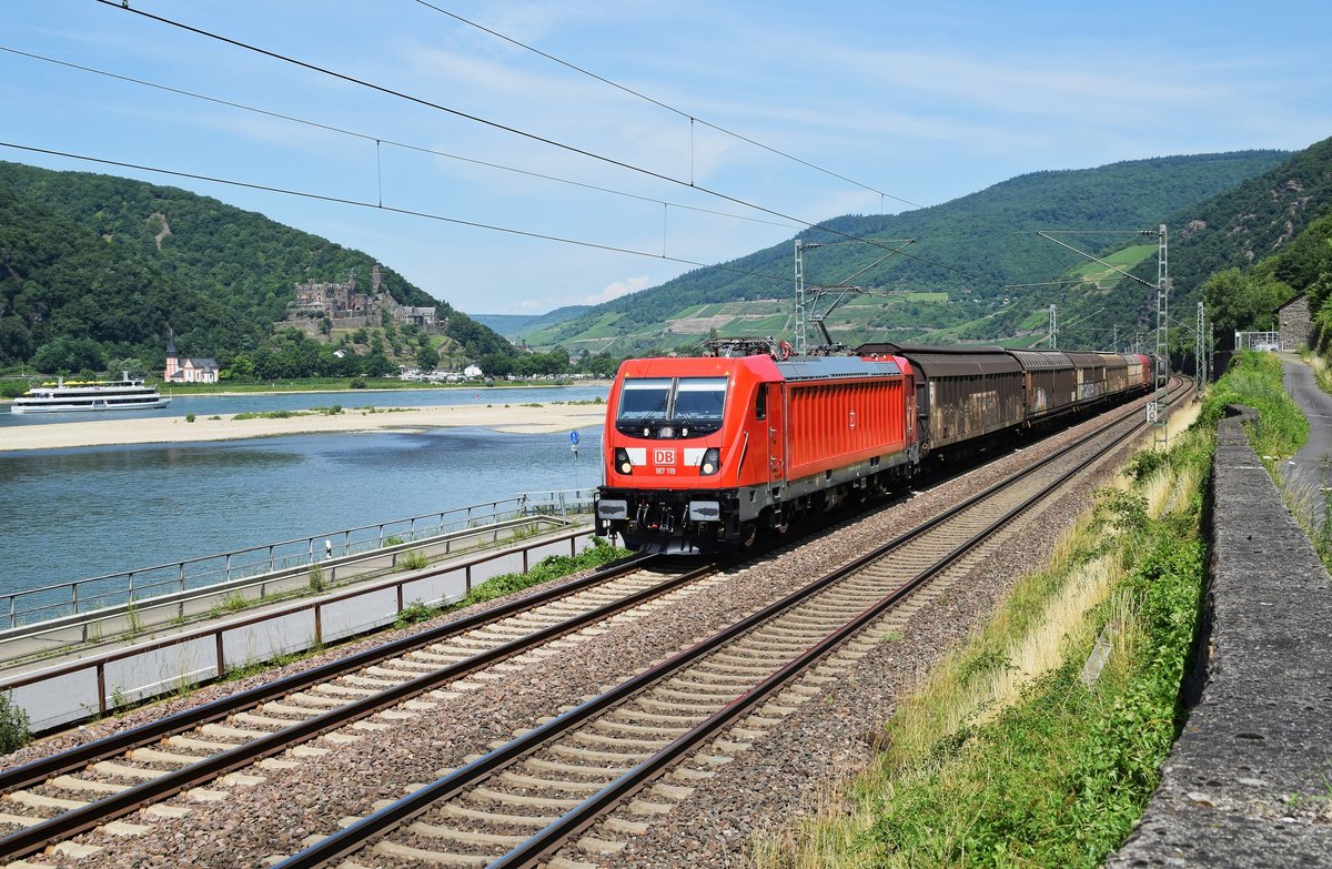 DB Cargo 187 119 befindet sich mit einem gemischten Güterzug am 07.07.17 auf der rechten Rheinstrecke bei Assmannshausen auf der Fahrt in Richtung Rüdesheim. Auf der anderen Rheinseite sind die Clemenskapelle und Burg Reichenstein zu erkennen. 