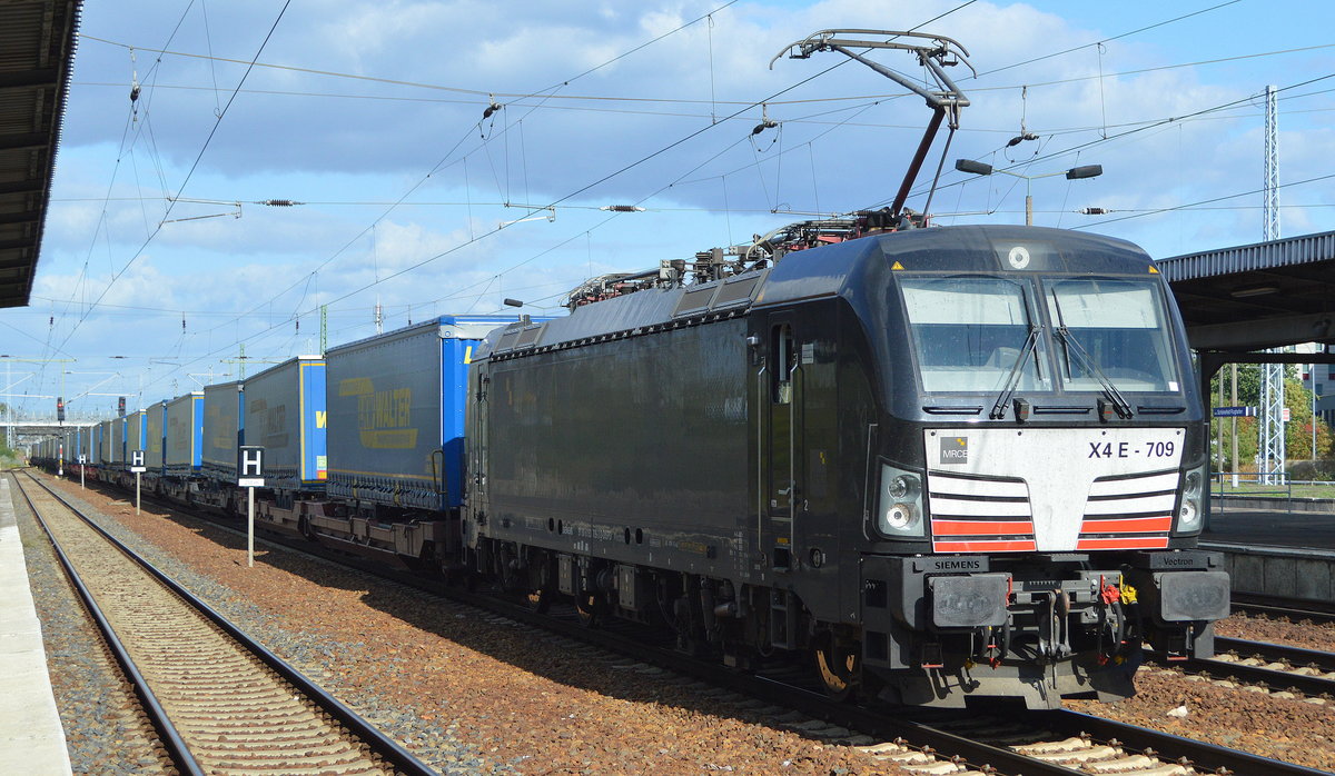 DB Cargo AG [D] mit der MRCE Vectron  X4 E - 709  [NVR-Nummer: 91 80 6193 709-3 D-DISPO] und Taschenwagenzug (LKW Walter Trailer) ab Rostock bei der Durchfahrt Bahnhof Flughafen Berlin Schönefeld am 18.09.19