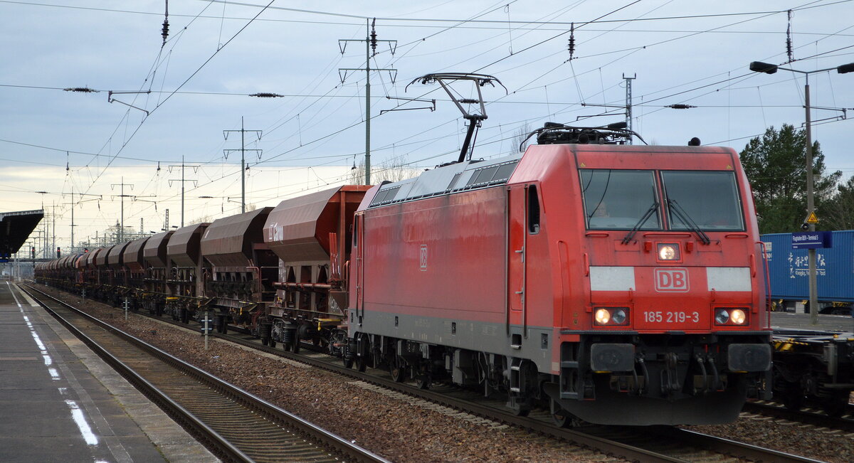DB Cargo AG [D] mit  185 219-3  [NVR-Nummer: 91 80 6185 219-3 D-DB] und Schotterzug am 24.02.22 Durchfahrt Bf. Flughafen BER - Terminal 5.