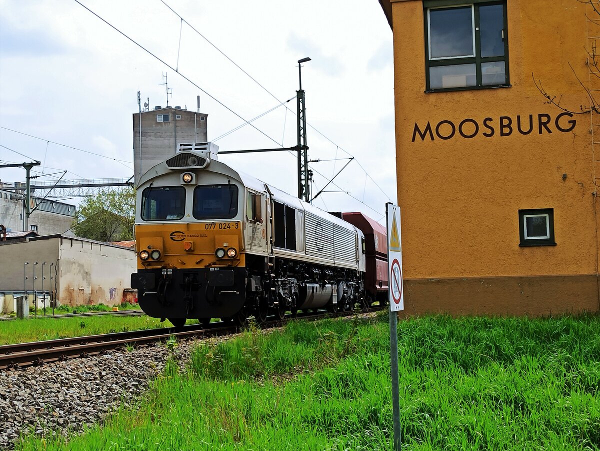 DB Cargo, Class 66, 77 024-3 ( 9287 0077 024-3 F-DB ) mit einem Schüttgutzug am Haltepunkt in Moosburg an der Isar am 2.5.2023
