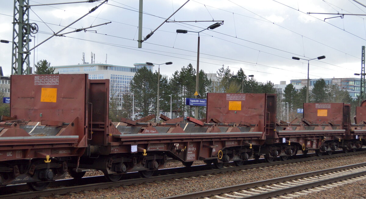 DB Cargo mit mehreren Drehgestell-Flachwagen mit Lademulden für Coils (leer) in einem gemischten Güterzug, in der Bildmitte der Wagen mit der Nr. 31 RIV 80 D-DB 4766 035-8 Shmmns 702 am 07.02.22 Durchfahrt Bf. Flughafen BER - Terminal 5.