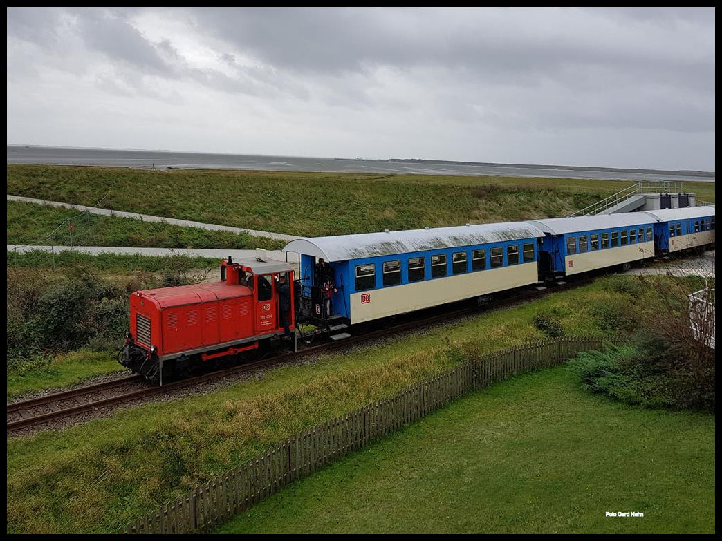 DB Diesellok 399105 kommt hier am 4.10.2017 mit einem Personenzug vom Hafen Wangerooge und fährt gerade durch das Deich Tor in Richtung Bahnhof.