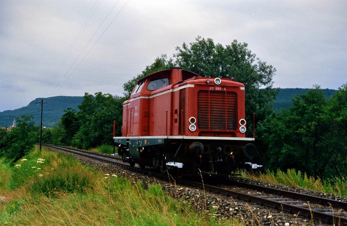 DB-Lok 211 089-8 rangiert vor dem Bahnhof Boll (Voralbbahn, DB), dazu ist sie relativ weit weg vom Bahnhof gefahren, so dass der Eindruck entstehen konnte, sie würde sich frei als einzelne Lokomotive auf der Bahnlinie bewegen. Datum leider nicht bekannt (evtl. 1985)