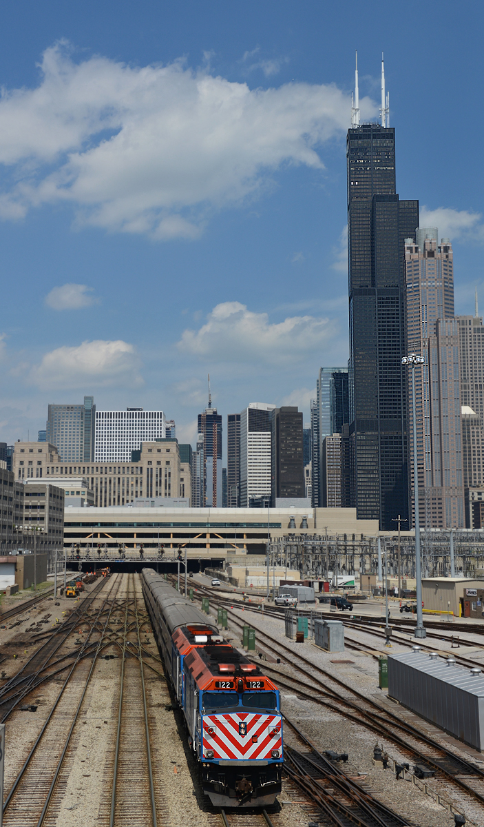 Dem Metra-Zug 1231 BNSF Rail nach Aurora war am 25. April 2016 ein EMD F40PH Tandem bestehend aus 122 und 105 vorgespannt, und wurde von mir bei der Ausfahrt aus der Chicago Union Station, im Hintergrund ist 527,3 Meter hohe Sear Tower (seit 2009 Willis Tower) zu sehen.