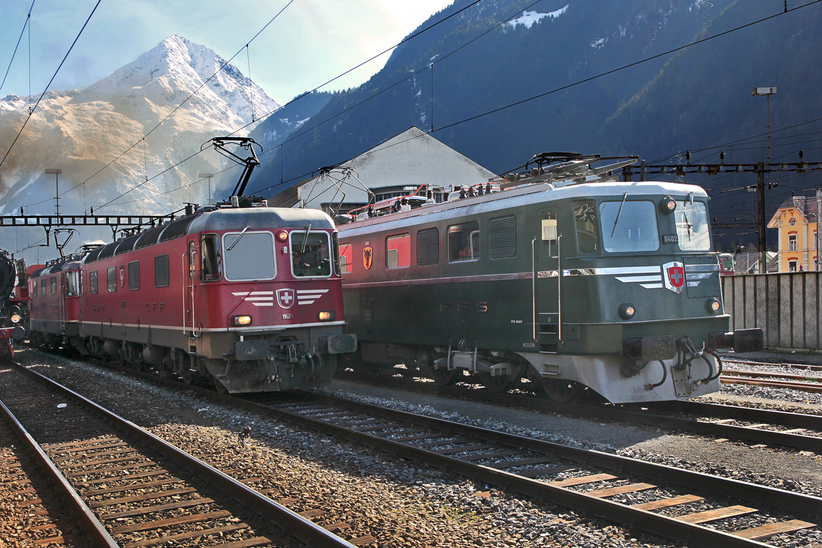 Den Bahnhof Erstfeld durchfährt Re 10/10 mit dem aufgeklebten Schnauz Re 6/6 11626 in Front und einem Containerzug und begegnet dabei dem Originalschnauz Ae 6/6  Uri  11402 ,links versucht die Dampflok 50 3673 derweil die Bergsicht einzunebeln.Bild vom 7.3.2015