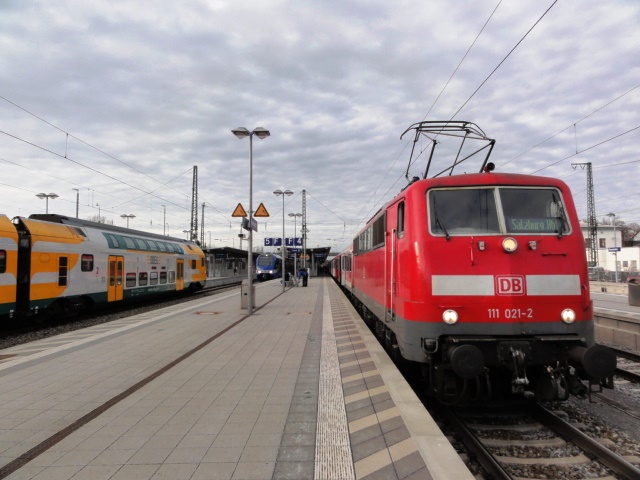 Der 15.12.2013 war der erste Betriebstag des Meridian im E-Netz Rosenheim. Jedoch verkehren bislang hauptsächlich Ersatzzüge, weil die heutige Eisenbahnindustrie erneut den Liefertermin für Neufahrzeuge nicht hat einhalten können. Der aus 111 021 und Bn-Wagen gebildete Zug lief genauso unter der Zuggattung ,,M'' wie der tatsächlich schon ausgelieferte FLIRT in der Mitte. Auch der abgestellte ODEG-KISS links ist ein Meridian-Ersatzzug.
Szenerie ist der Bahnhof Rosenheim