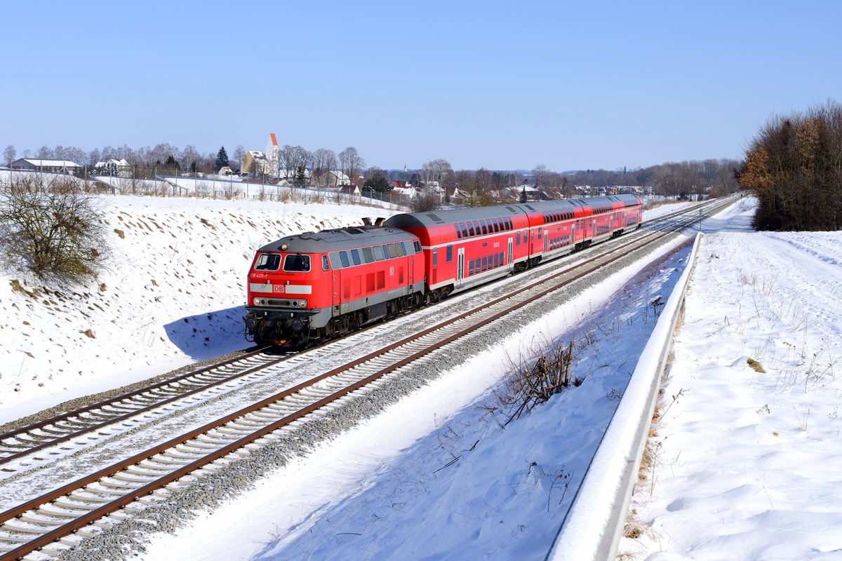 Der 25. Februar 2018 war ein klarer, allerdings eisig kalter Tag. Er wurde genutzt, die Gegend um Kaufering aufzusuchen. Bei Epfenhausen konnte ich die 218 425 mit ihrem RE 57500 nach Marktoberndorf aufnehmen. Diese ursprünglich sehr schöne Fotostelle ist aufgrund eines Sonnenkollektorenfeldes im Hintergrund und des Kabelkanals praktisch unbrauchbar geworden. Die geschlossene Schneedecke kaschierte die störenden Elemente jedoch gnädig.