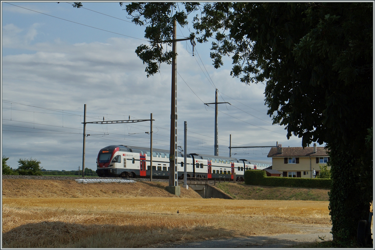 Der alte Baum und das zweckentfremdete Bahnwärterhaus kurz nach Allaman verbreiten selbst auf der modernen Strecke Lausanne Genève noch einen Hauch entspannende Nostalgie. 
Ein SBB RABe 511 ist als RE 3218 von Vevey nach Genève unterwegs.
8. Juli 2015