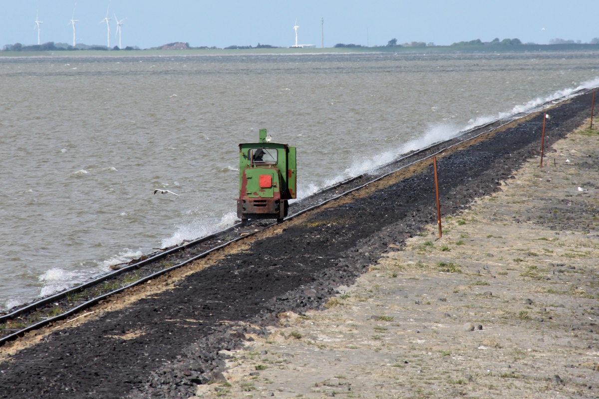 Der Baggerfahrer vom Festland hat Feierabend und fährt mit seinem Dienstfahrzeug, Lok 2 des LKN-SH (Schöma 4025, Typ CHL 20G, Bauj. 1975) von Langeness in Richtung Festland. Die Aufn. entstand am 05.06.2012 vom Aussichtspunkt und zeigt warum der Bau eines erhöhten Dammes zw. Oland und Langeness notwendig war, nicht mehr viel und das Wasser schwappt über.